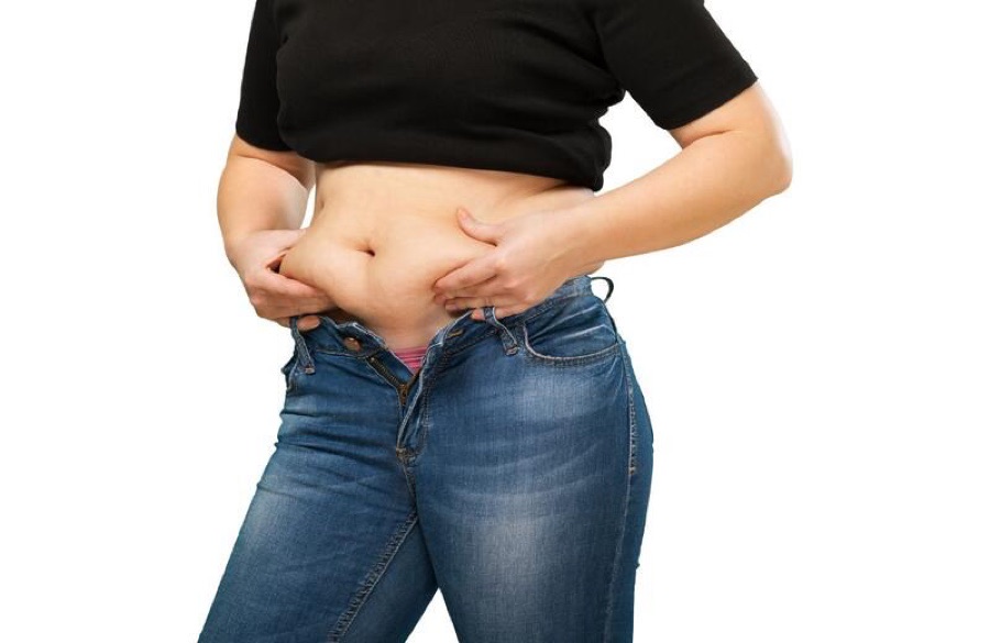 Mulher com a barriga estufada segurando a região abdominal